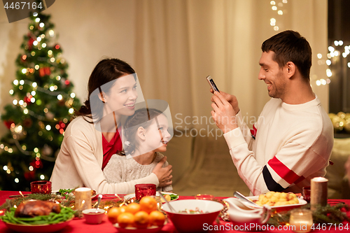 Image of happy family taking picture at christmas dinner