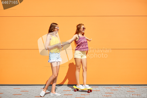 Image of teenage girls riding skateboard on city street