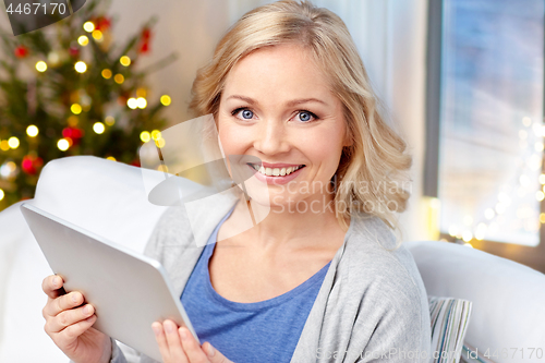 Image of happy woman with tablet pc at home on christmas