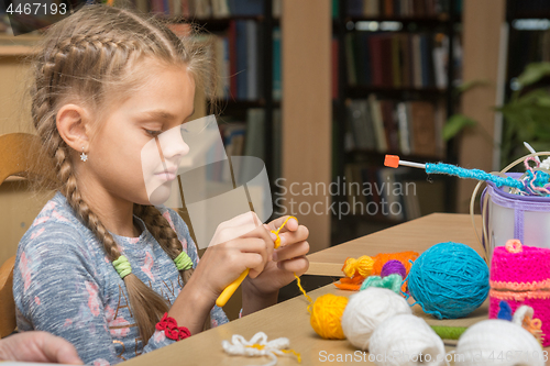 Image of The girl knits embroidery in the school library