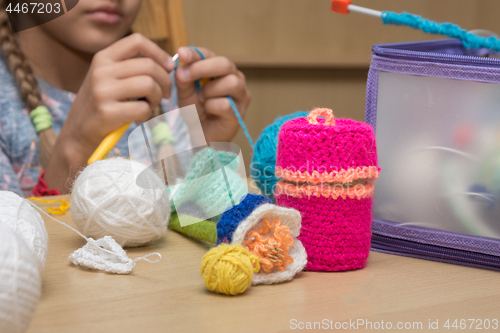 Image of Childrens crafts-embroidery lying on the table, in the background the girl knits