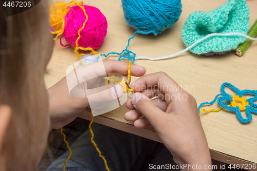 Image of Hands of a child are embroidered with threads using a hook