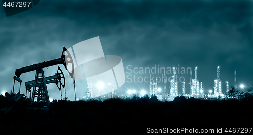 Image of Pump jack and grangemouth refinery at night.