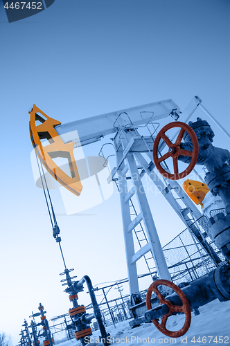 Image of Oil pump jack and wellhead in the oilfield