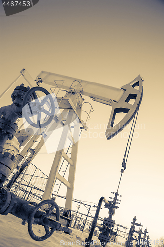 Image of Oil pump jack and wellhead in the oilfield