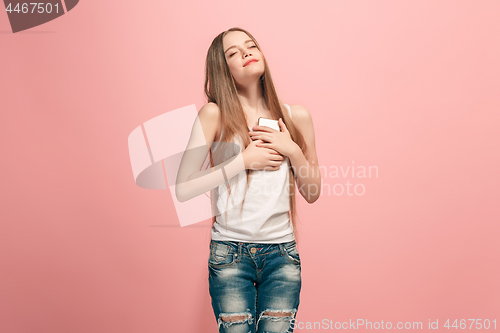 Image of The happy teen girl standing and smiling against pink background.