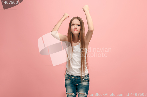 Image of Portrait of angry teen girl on a pink studio background