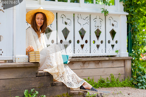 Image of woman in a white dress and a hat with books