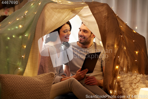 Image of happy couple with tablet pc in kids tent at home