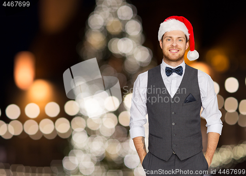 Image of happy man in santa hat and suit at christmas