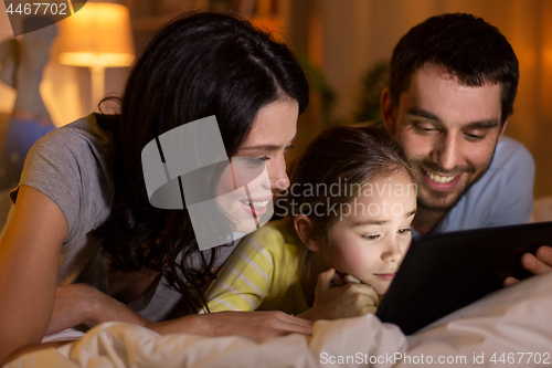 Image of family with tablet pc in bed at night at home