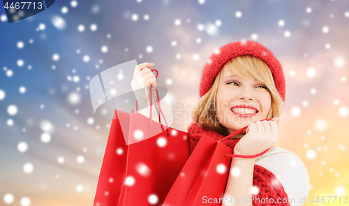 Image of woman with red shopping bags over snow background