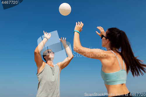 Image of happy couple playing volleyball on summer beach