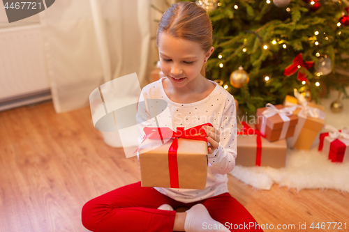 Image of smiling girl with christmas gift at home