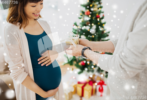 Image of husband giving christmas present to pregnant wife