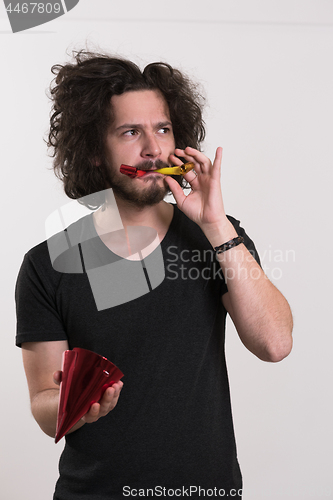 Image of Portrait of a man in party hat blowing in whistle