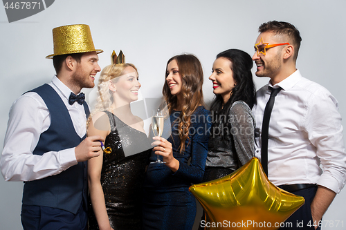 Image of happy friends with golden party props posing