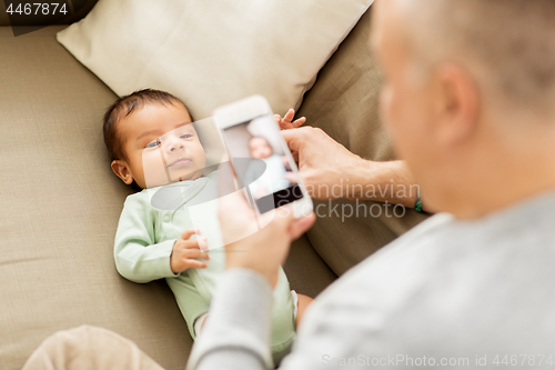 Image of father photographing baby by smartphone