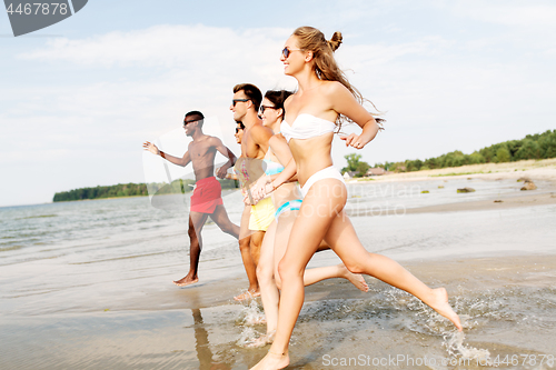 Image of happy friends running on summer beach