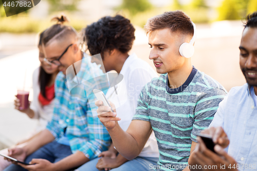 Image of man with friends listening to music on smartphone