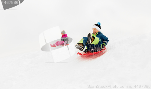 Image of happy kids sliding on sleds down hill in winter