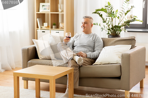 Image of man drinking red wine from glass at home