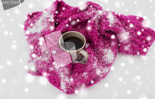 Image of tea or coffee mug and winter scarf on snow