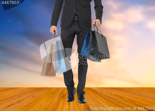 Image of close up of man in suit with shopping bags