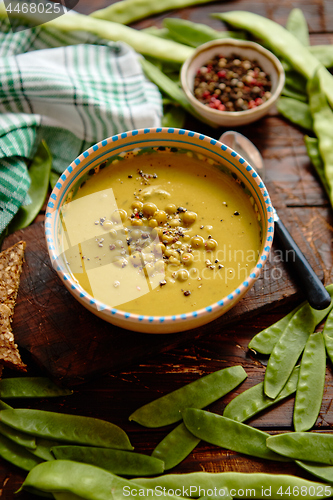 Image of Green pea cream soup in grey bowl