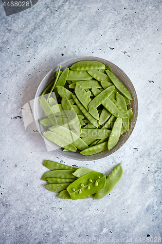 Image of Fresh green peas in white ceramic bowl on gray stone background