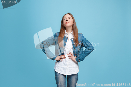 Image of The happy teen girl standing and smiling against blue background.