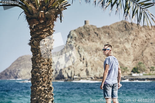 Image of Man with sunglasses in shadow of palm tree