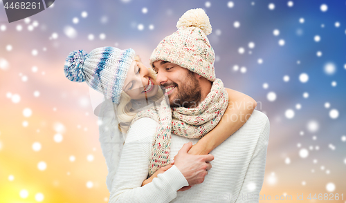 Image of happy couple in winter clothes hugging over snow