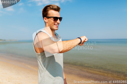 Image of happy man with fitness tracker on summer beach