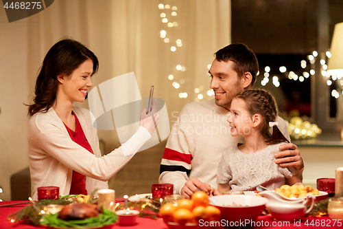 Image of happy family taking picture at christmas dinner