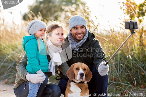 Image of happy family with dog taking selfie in autumn