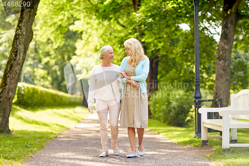 Image of daughter with senior mother walking at summer park