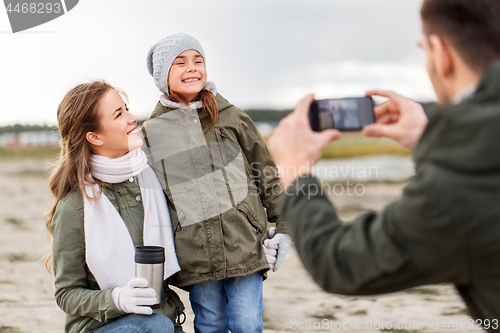 Image of family photographing by smartphone on autumn beach