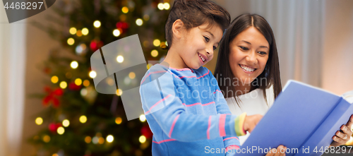 Image of mother and daughter reading book on christmas