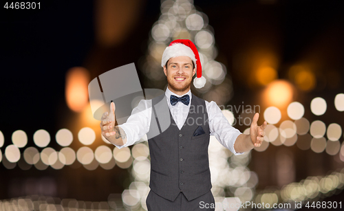 Image of happy man in santa hat holding something imaginary