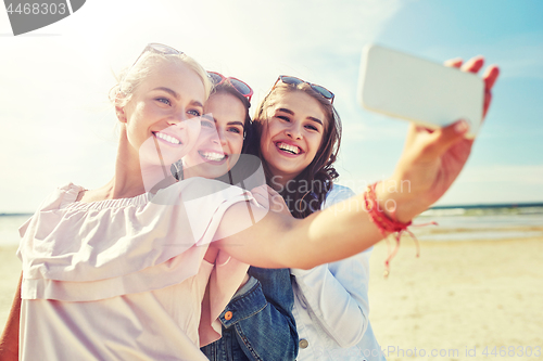 Image of group of smiling women taking selfie on beach