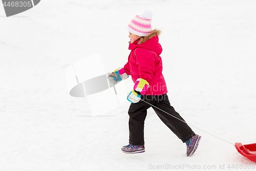 Image of little girl with sleds on snow hill in winter