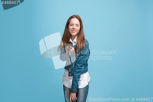 Image of The happy teen girl pointing to you, half length closeup portrait on blue background.