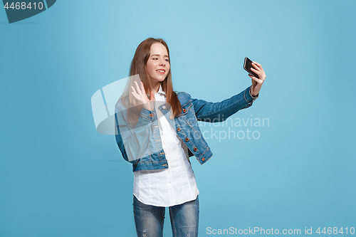 Image of The happy teen girl standing and smiling against pink background.