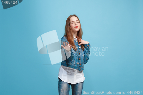 Image of The happy teen girl standing and smiling against blue background.