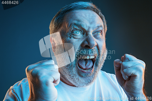 Image of The senior emotional angry man screaming on blue studio background