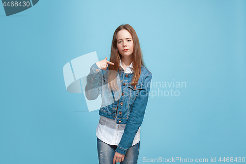 Image of Beautiful female half-length portrait on blue studio backgroud. The young emotional teen girl