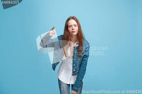 Image of Beautiful female half-length portrait on blue studio backgroud. The young emotional teen girl