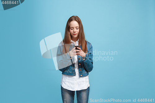 Image of The happy teen girl standing and smiling against blue background.