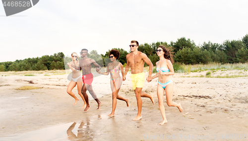 Image of happy friends running on summer beach